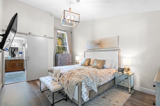 bedroom with hardwood / wood-style floors, a notable chandelier, a textured ceiling, and connected bathroom