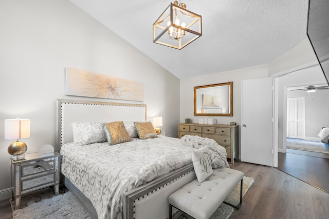 bedroom featuring a chandelier, a textured ceiling, dark hardwood / wood-style floors, and lofted ceiling