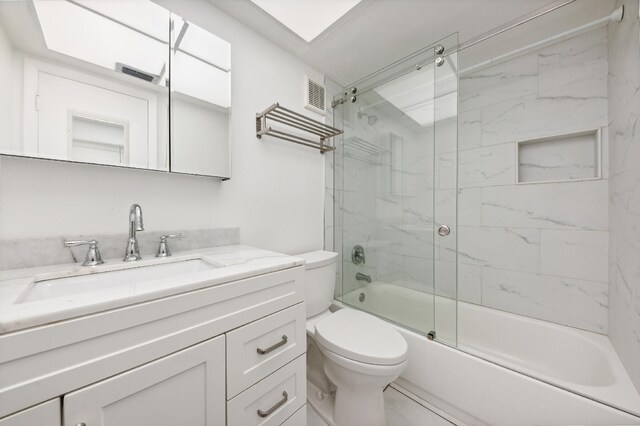 full bathroom featuring vanity, bath / shower combo with glass door, and toilet