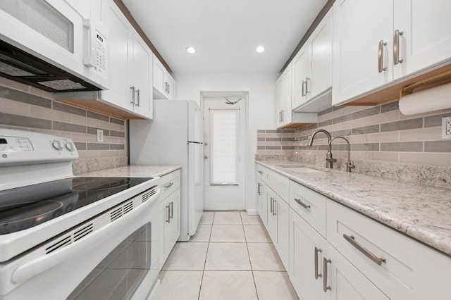 kitchen with white appliances, sink, light stone countertops, light tile patterned floors, and white cabinetry