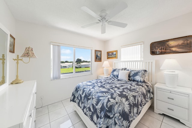 bedroom featuring ceiling fan, light tile patterned floors, and a textured ceiling