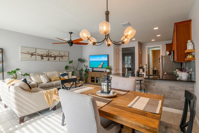 tiled dining room featuring sink and ceiling fan with notable chandelier