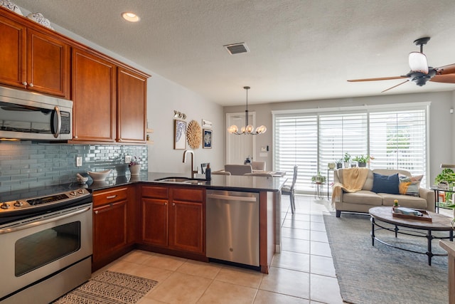 kitchen featuring pendant lighting, sink, light tile patterned floors, kitchen peninsula, and stainless steel appliances