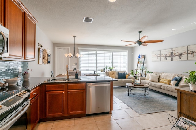 kitchen with sink, kitchen peninsula, stainless steel appliances, and light tile patterned floors