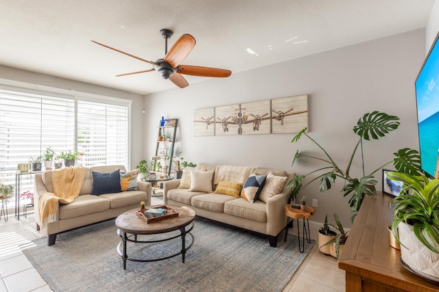 living room with ceiling fan, light tile patterned floors, and a textured ceiling