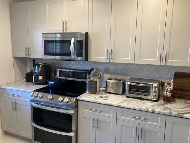 kitchen with light stone countertops, backsplash, and appliances with stainless steel finishes