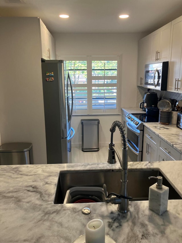 kitchen featuring light stone counters, white cabinetry, sink, and appliances with stainless steel finishes