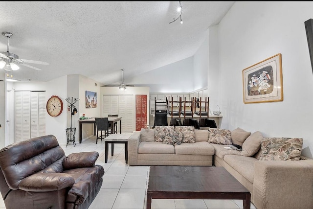 living room with a textured ceiling, high vaulted ceiling, ceiling fan, and light tile patterned flooring