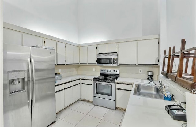 kitchen featuring white cabinets, appliances with stainless steel finishes, light tile patterned floors, and sink