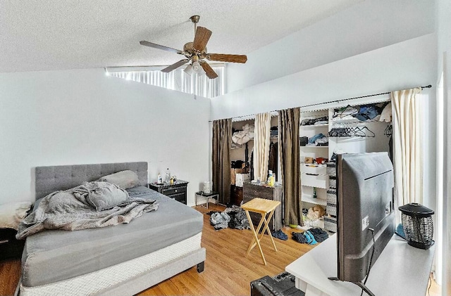 bedroom featuring hardwood / wood-style flooring, ceiling fan, a textured ceiling, and vaulted ceiling