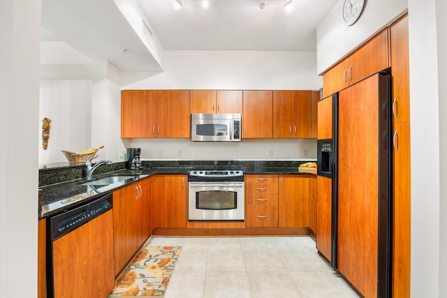 kitchen with sink, light tile patterned floors, stainless steel appliances, and dark stone counters