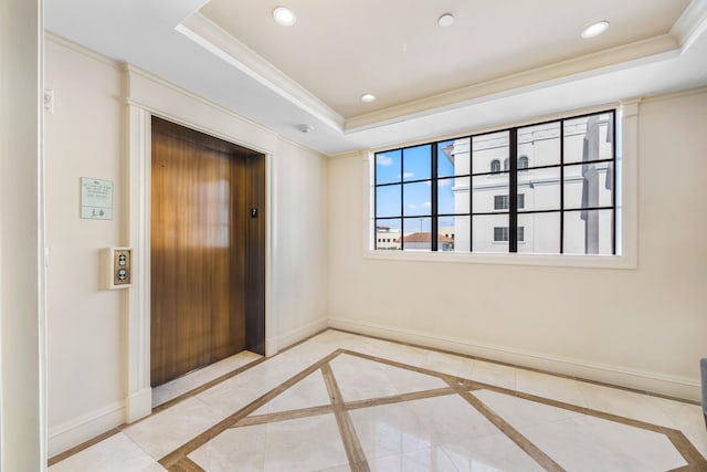 unfurnished room featuring a tray ceiling, elevator, crown molding, and tile patterned floors