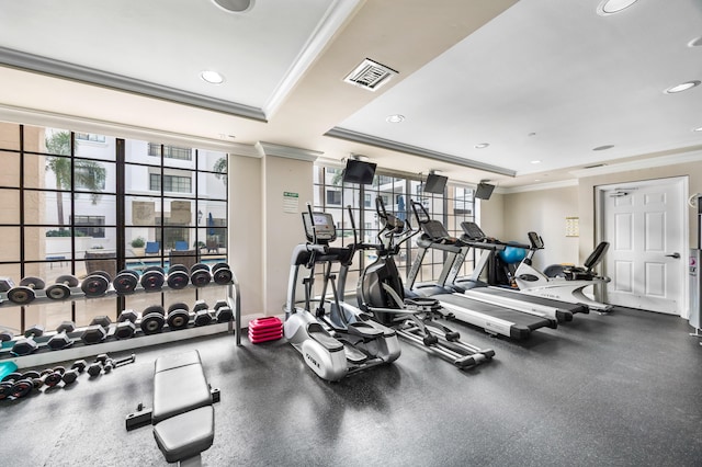 workout area featuring a raised ceiling and ornamental molding