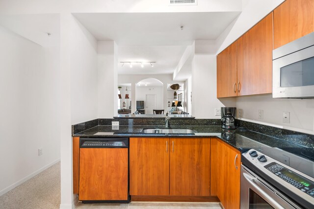 kitchen with dark stone countertops, dishwasher, stainless steel range with electric stovetop, and sink