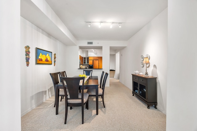 dining space featuring rail lighting and light colored carpet