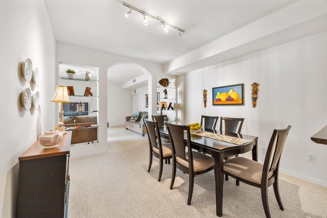 carpeted dining area featuring rail lighting