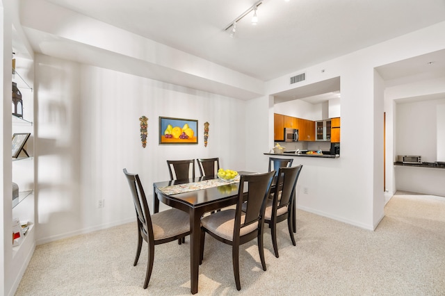 dining room featuring track lighting and light colored carpet