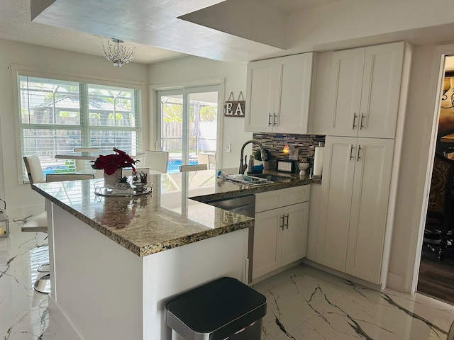 kitchen with a kitchen breakfast bar, a textured ceiling, sink, dark stone countertops, and white cabinetry