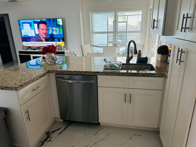 kitchen with stainless steel dishwasher, white cabinets, sink, and stone counters