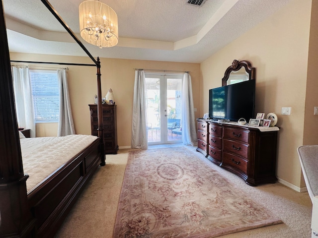 carpeted bedroom with access to outside, french doors, a raised ceiling, a textured ceiling, and a chandelier