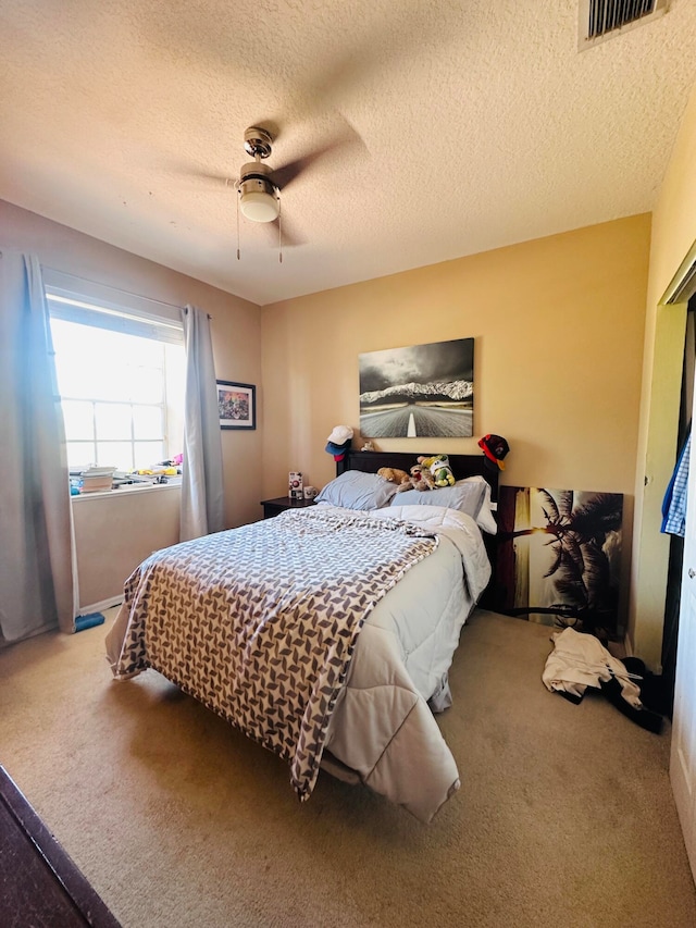 bedroom with a textured ceiling, carpet floors, and ceiling fan