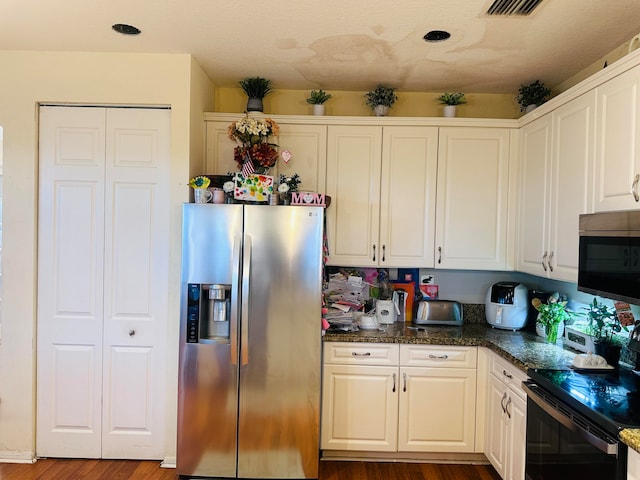 kitchen featuring white cabinets, dark hardwood / wood-style flooring, dark stone countertops, and appliances with stainless steel finishes