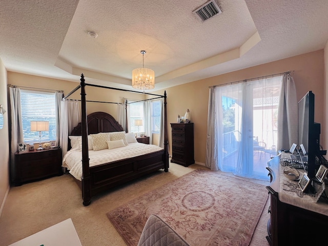 bedroom with access to exterior, a textured ceiling, a tray ceiling, light colored carpet, and a chandelier