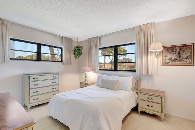 bedroom with multiple windows, light carpet, and a textured ceiling