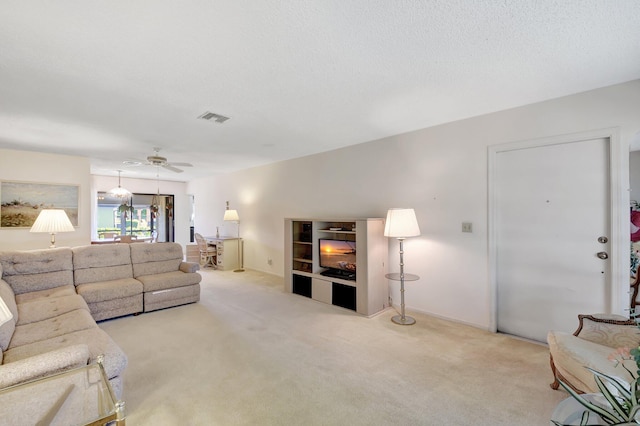 carpeted living room with ceiling fan, a fireplace, and a textured ceiling