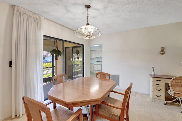 carpeted dining area with a chandelier and a textured ceiling