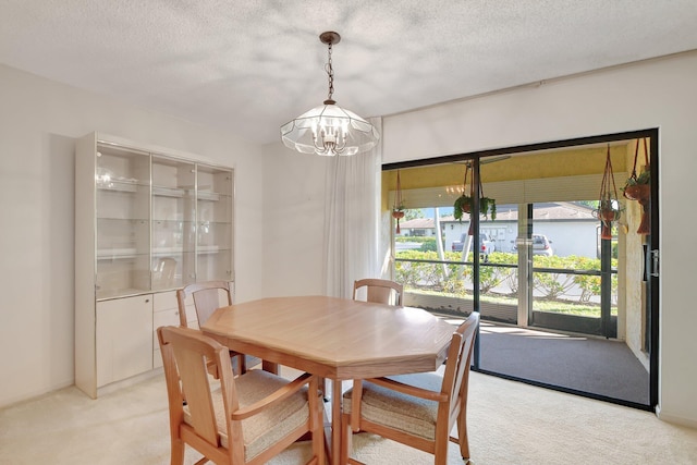 dining space with an inviting chandelier, light colored carpet, and a textured ceiling