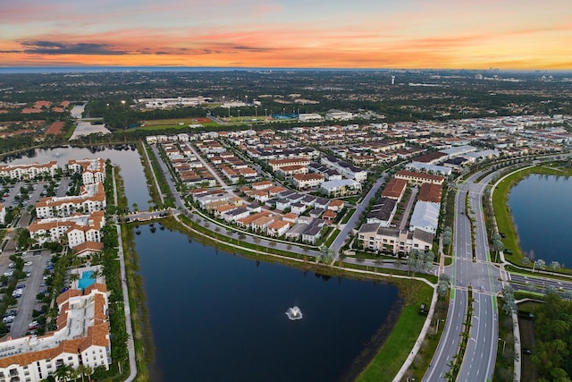 aerial view at dusk featuring a water view