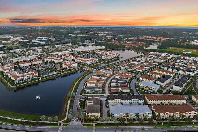 aerial view at dusk featuring a water view