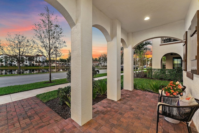 patio terrace at dusk featuring a water view