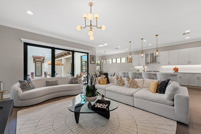 living room featuring a notable chandelier, sink, crown molding, and light hardwood / wood-style flooring