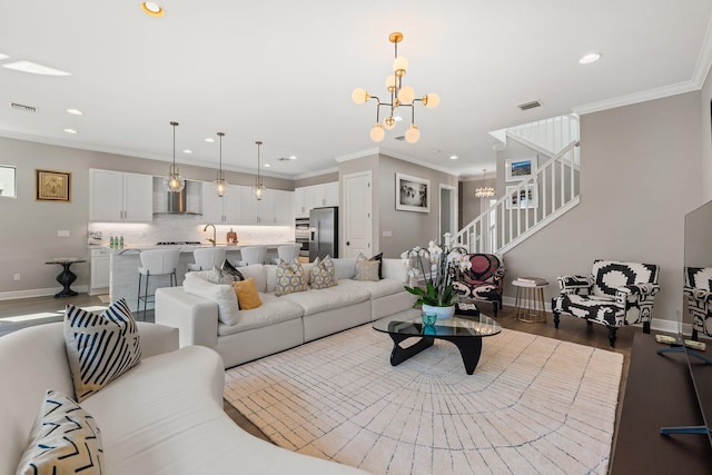 living room with wood-type flooring, an inviting chandelier, ornamental molding, and sink