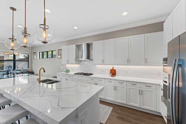 kitchen featuring white cabinetry, sink, stainless steel appliances, and wall chimney range hood