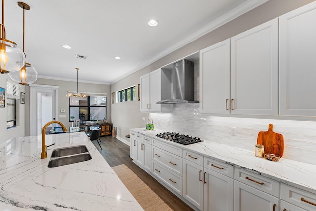 kitchen with sink, wall chimney exhaust hood, dark wood-type flooring, gas stovetop, and pendant lighting