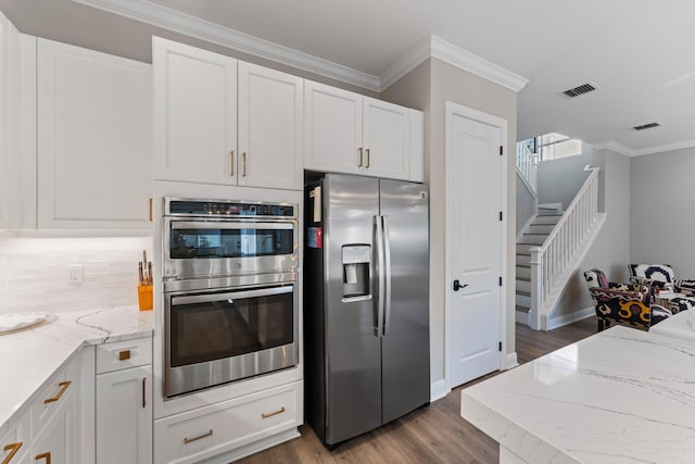 kitchen with ornamental molding, tasteful backsplash, white cabinetry, wood-type flooring, and stainless steel appliances