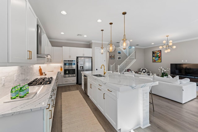 kitchen with appliances with stainless steel finishes, sink, white cabinetry, and an island with sink