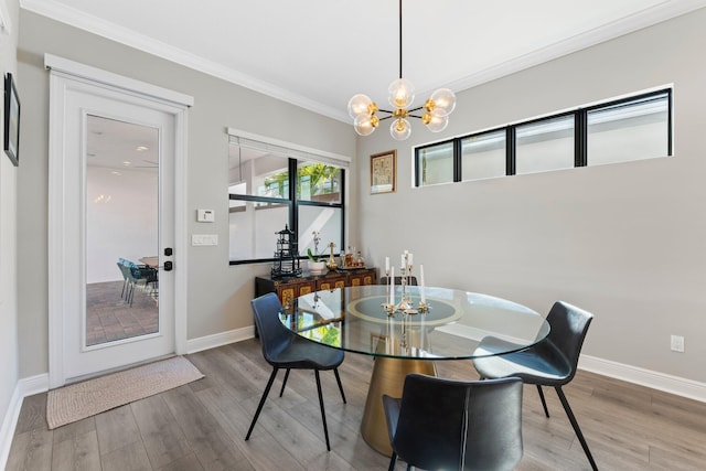 dining space featuring hardwood / wood-style floors, crown molding, and an inviting chandelier