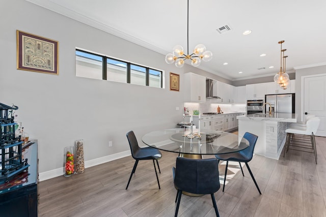 dining space featuring light wood-type flooring, an inviting chandelier, and crown molding