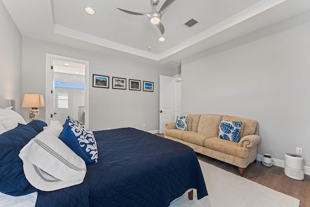 bedroom featuring ceiling fan, dark hardwood / wood-style floors, and a raised ceiling