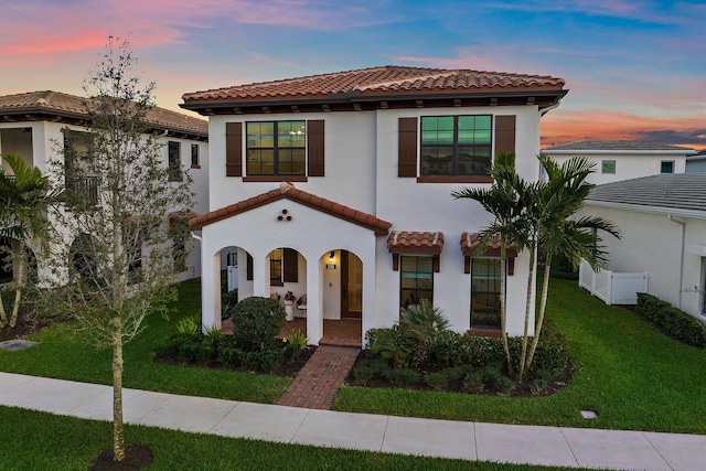 mediterranean / spanish home featuring a lawn and covered porch