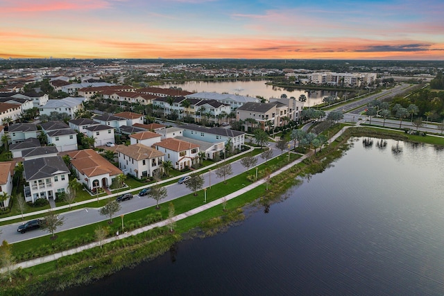 aerial view at dusk featuring a water view