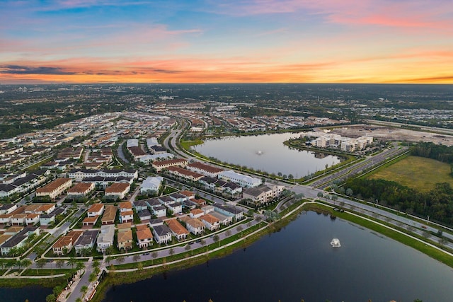 aerial view at dusk featuring a water view