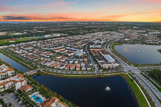 aerial view at dusk featuring a water view