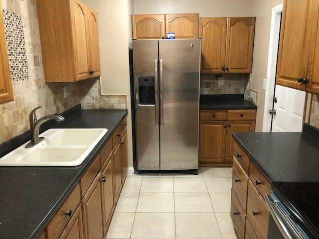 kitchen featuring decorative backsplash, stainless steel refrigerator with ice dispenser, light tile patterned floors, and sink