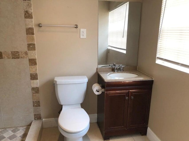 bathroom with tile patterned flooring, vanity, toilet, and a wealth of natural light