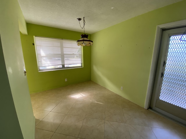 unfurnished dining area featuring light tile patterned floors and a textured ceiling